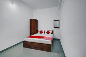 迪布鲁加尔Super OYO Flagship The Mahalaxmi Inn的白色客房内的一张带红色枕头的床
