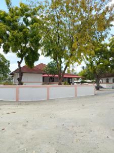 达拉万度Turtle Inn Dharavandhoo的树木丛生的房子前的白色围栏