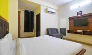 印多尔Hotel Shubhshree的一间卧室配有一张床、一台电视和一把椅子