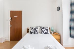 伦敦Wood Green Budget Rooms - Next to Mall & Metro Station - 10 Min to City Center的一间卧室配有一张带白色床单的床和木门。