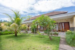 珀尼达岛Omah Nusa Villa RedPartner的前面有棕榈树的房子