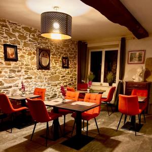 Les Champs-GérauxLe Manoir des Haies SPA的一间设有橙色椅子和石墙的用餐室