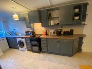 斯莱戈Newly Furnished 5 Bedroom Gem in Sligo的厨房配有蓝色橱柜、洗衣机和烘干机