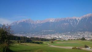 因斯布鲁克Appartements Wessely am Golfplatz Lans Innsbruck的绿色的田野,以城市和山脉为背景