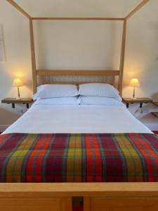 YarrowThe Gordon Arms Restaurant with Rooms的一张带条纹毯子的床和两张台灯