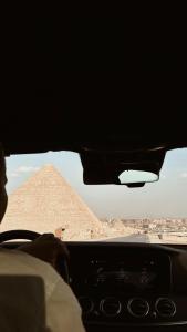 开罗Pyra Hospitality West Pyramids Cairo的金字塔前驾驶汽车的人
