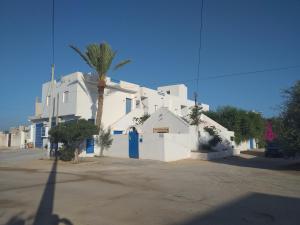 乌姆苏克Dar Janis Djerba دار يانيس جربة的白色的建筑,有蓝色的门和棕榈树