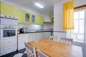 佩尼契Peniche Sun & Surf Apartment的厨房配有木桌和黄色橱柜。