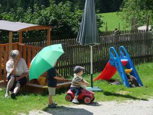 圣卡瑟林阿哈Pircherhof - Urlaub und Erholung im Troadkost'n的一名妇女和两名儿童在游乐场玩耍