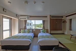 北谷町Aqua Resort in Chatan的带窗户的客房内的两张床