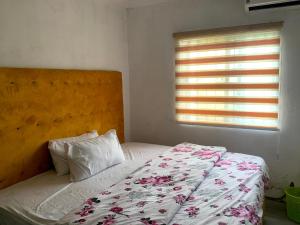 莱基New Travellers Lodge Sangotedo Lagos的一间卧室配有一张带花卉床罩的床和窗户。