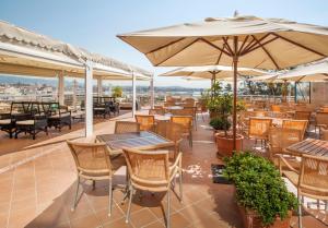 马略卡岛帕尔马加泰罗尼亚马略卡酒店的一个带桌椅和遮阳伞的庭院