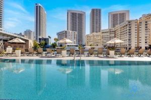 哈兰代尔海滩Infinite Views, Amazing Pool, Gym, Near Beach的城市里一个带椅子和遮阳伞的游泳池