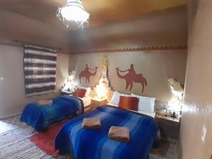 梅尔祖卡拉比博特奥博格宾馆的一间卧室配有两张带蓝色床单和壁画骆驼的卧室