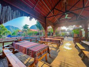宁平Trang An Quynh Trang Happy Homestay & Garden的餐厅设有木桌和长凳,后面是群山