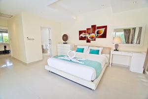 乔木提恩海滩热带泳池别墅的一间白色卧室,房间内设有一张大床