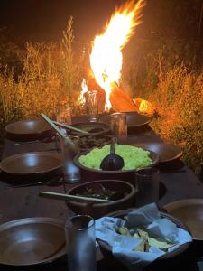 加姆波勒Peacock Hill Glamp的一张桌子,上面有食物和背景的火