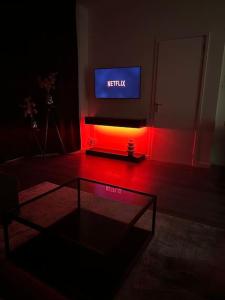 海牙Serenity Residence的一间带电视和桌子的客厅以及红灯