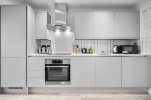伯明翰Stylish 2 Bedroom Apartment Close to Everything的厨房配有白色橱柜和炉灶烤箱。