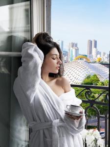 岘港CENTRAL BOUTIQUE HOTEL的把一个女人裹在毛巾里,拿着一杯咖啡
