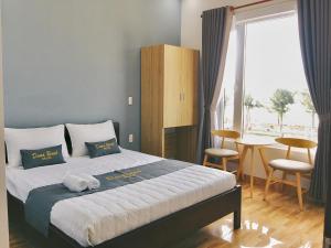 岘港DanaBeach Motel的一间卧室配有一张床和一张桌子及椅子
