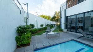 米德兰Chic Modern Midrand Escape的一座建筑旁的庭院,设有游泳池和椅子