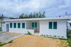 阿雷西博Centrally located Villa with 3 Pools -Food & Beach walking distance的白色的房屋,设有绿色的窗户