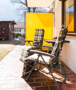 贝里斯泽尔Hotel Garni Effland的两把椅子坐在一个黄色墙壁的庭院里