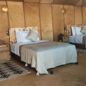 梅尔祖卡Sahara Luxurious Camp的一间帐篷内带两张床的卧室