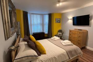 斯卡伯勒Seaside Hideaway - Free Onstreet Parking的一间卧室配有一张黄色墙壁的床和电视