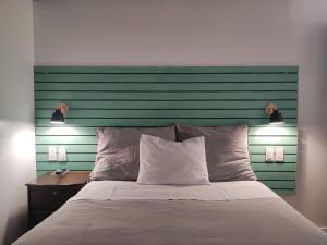 库斯科Casa Agustina的一张带绿色床头板的床,上面有两盏灯
