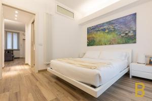 米兰BePlace Apartments in Gioia的白色卧室设有一张大床和墙上的绘画