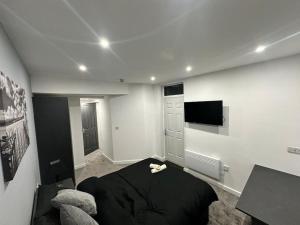 Beeston HillLuxurious 2 bedroom flat的一间卧室配有一张黑色的床和一台平面电视。