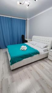 PrigorodnyyKamal Apart的一间卧室配有一张白色的床和蓝色的毯子