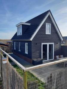 GrijpskerkeNIEUW Vakantiewoning Nimmerdor, Grijpskerke, dichtbij strand en stad的一间黑色的小房子,设有木甲板