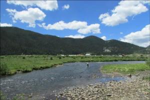 南福克Ute Bluff Lodge, Cabins and RV park的站在田野的河流中的人