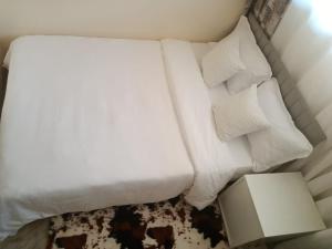 内罗毕The Pearl Cage Gigiri-Near US Embassy的一张带两个枕头和一盏灯的白色床