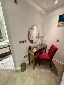 朴次茅斯Gunwharf Quays Harbour Apartments的一间卧室配有书桌、红椅和镜子