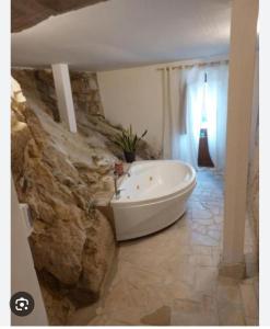 Pennapiedimontehotel scaffe的浴室配有白色浴缸和石墙