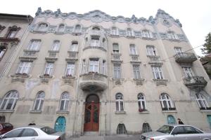 布达佩斯泽内斯豪斯公寓的一座大型建筑,前面有汽车停放