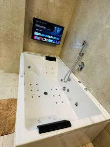 海得拉巴Luxurious Independent villa in Gachibowli的浴室设有带电视的白色浴缸。