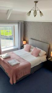 恩布尔顿Blue Bell Inn的卧室配有一张带粉红色枕头的大床