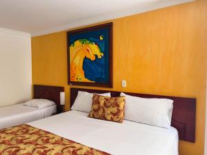 佩雷拉Hotel Luxor Pereira的酒店客房设有两张床,并画有一幅马