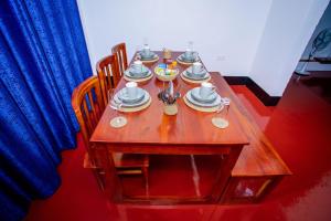 莫希Royal Homestay的一张木桌,上面有盘子和盘子