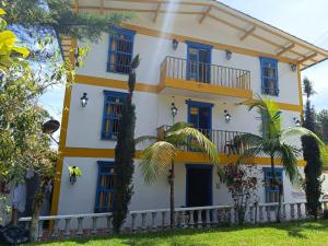 瓜塔佩Hotel sol del lago的黄色和白色的建筑,拥有蓝色的窗户和棕榈树