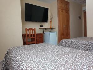 巴里亚纳比阿特丽斯酒店 的一间卧室设有两张床,墙上配有电视。