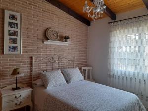 CamuñasVIVENCIAS casa rural para 10 personas的一间卧室设有一张床和砖墙