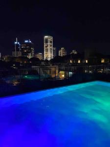 蒙得维的亚More Echevarriarza apartamento de estreno!!的蓝色的游泳池,晚上有城市天际线