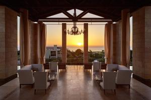 RomanuThe Romanos, a Luxury Collection Resort, Costa Navarino的一间带椅子和吊灯的房间,享有日落美景