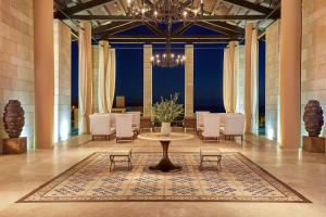 RomanuThe Romanos, a Luxury Collection Resort, Costa Navarino的大型客房配有桌椅和吊灯。
